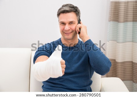 Man With Fractured Hand Showing Thumb-up Talking On Cellphone