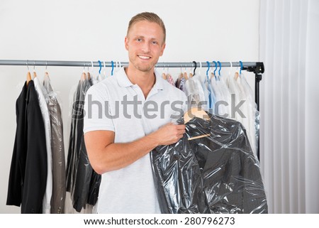 Young Happy Man Holding Coat In Dry Cleaning Store