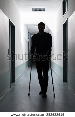 Silhouette Of Disabled Man Walking With Crutches In Hospital