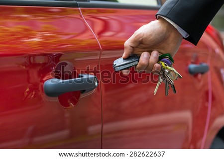 Close-up Of A Person\'s Hand Holding A Car\'s Remote Control Pointing To The Door