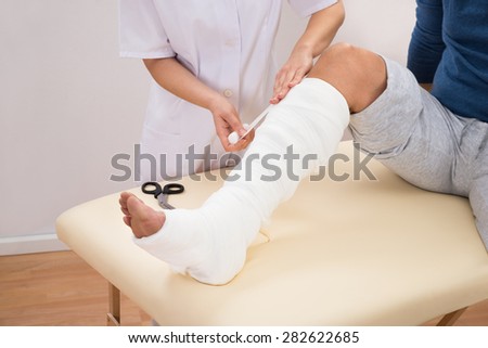 Close-up Of A Female Doctor Bandaging Patient\'s Leg