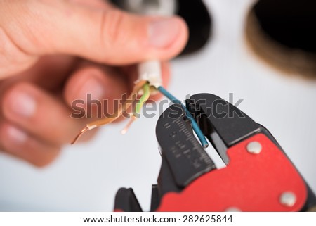 Closeup Of Electrician Hands Stripping Electrical Wires For Wall Socket
