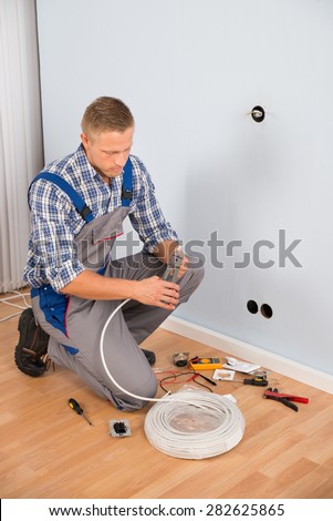 Young Electrician Working With Wire With Plier In House