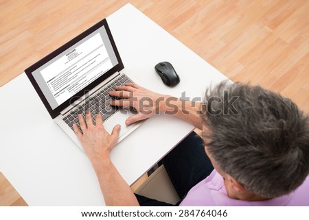 High Angle View Of A Man Preparing Resume On Laptop