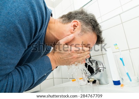 Close-up Of A Man Washing Face In Bathroom