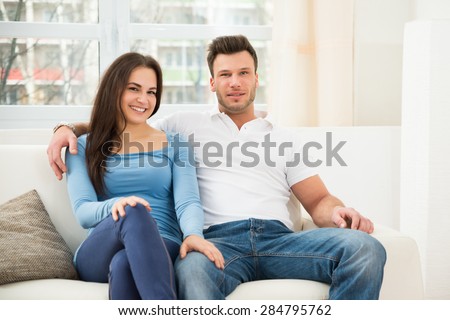 Portrait Of Happy Smiling Couple Sitting On Couch At Home