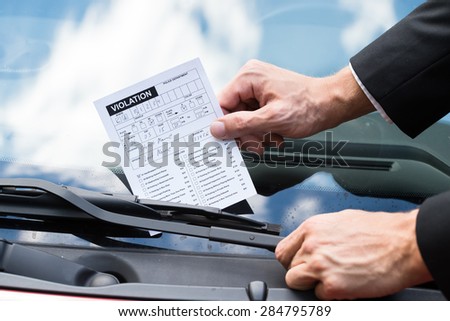 Close-up Of A Man Taking Parking Ticket On Car\'s Windshield