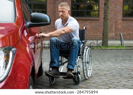 Portrait Of A Handicapped Man Sitting On Wheelchair Opening Door Of A Car