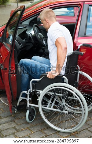 Handicapped Man Sitting On Wheelchair Boarding In His Car
