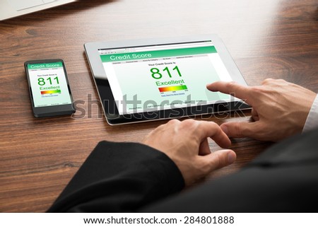 Close-up Of A Businessman Checking Credit Score Online On Digital Tablet And Cellphone