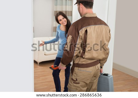 Happy Young Woman Welcoming Male Plumber At Home