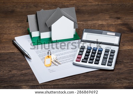 House Model On Contract Paper With Keys And Calculator Kept On Wooden Desk