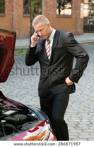 Stressed Young Man Calling On Cellphone For Service With His Breakdown Car