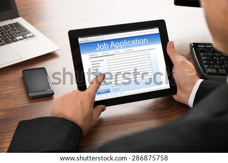 Close-up Of Businessman Filling Online Job Application On Digital Tablet