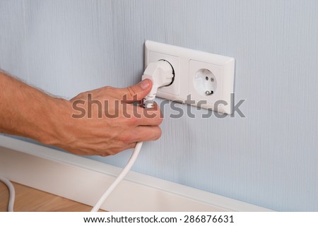Closeup Of Hand Inserting An Electrical Plug Into A Wall Socket