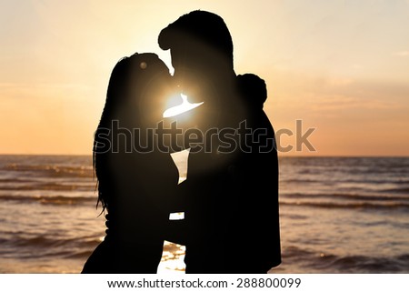 Silhouette Of Couple Kissing In Front Of Sea At Beach During Sunset