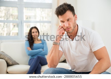 Defocused Woman Sitting On Couch In Front Of Sad Young Man
