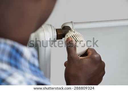 Close-up Of Person Hands Adjusting Thermostat Radiator Valve