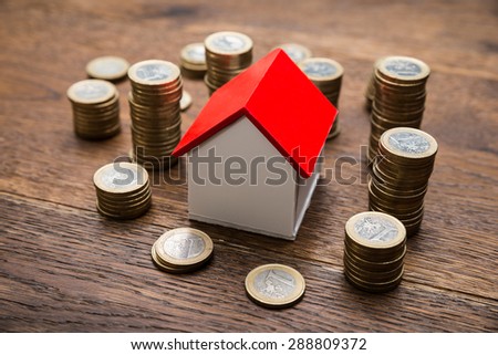House Of Model With Coins On Wooden Table