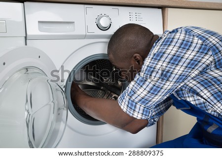 Close-up Of Young African Technician Repairing Washing Machine