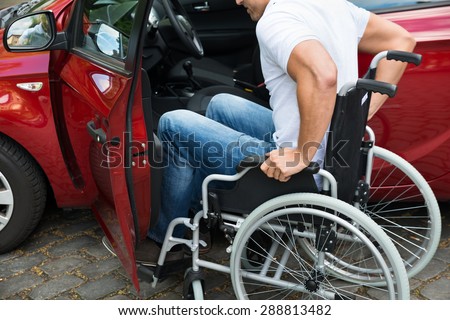 Close-up Of A Disabled Man In Wheelchair Getting In His Car