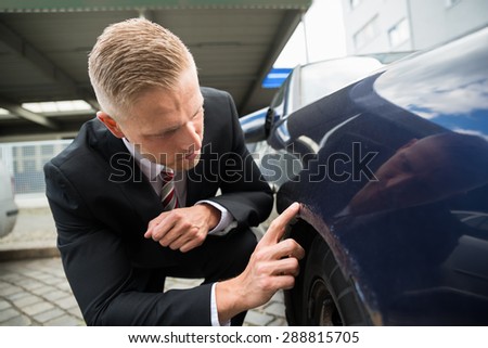 Portrait Of Young Man Looking For Scratches On His Car