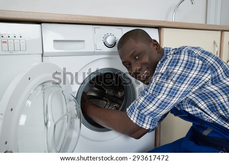 Close-up Of Young Happy African Technician Fixing Washing Machine