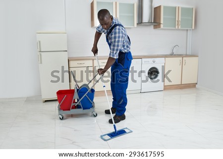 African Male Worker In Overall Cleaning Floor With Mop