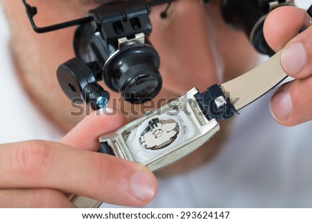 Close-up Of Young Man Looking Wrist Watch With Loupe