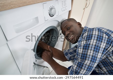 Close-up Of Young African Technician Repairing Washing Machine