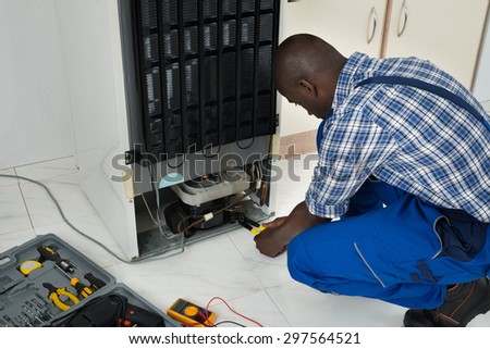 Young African Technician Fixing Refrigerator With Worktool