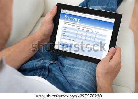 Close-up Of Person On Sofa With Digital Tablet Showing Survey Form