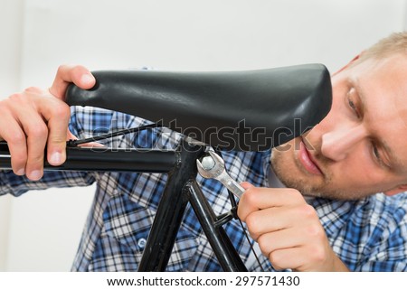 Portrait Of Young Man Tightening The Bolts Of Bicycle Seat With Spanner