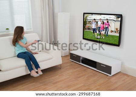 Girl Sitting On Sofa Watching Television In House