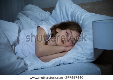 Cute Girl Sleeping On Bed In Dark Bedroom