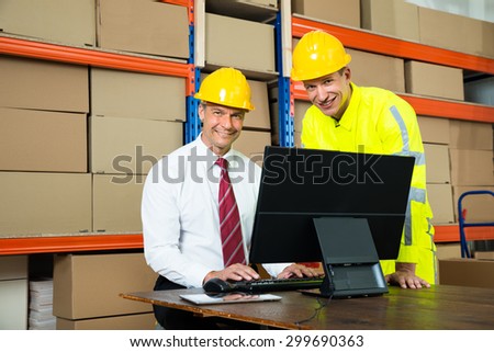 Portrait Of Happy Warehouse Worker And Manager Using Computer In A Warehouse