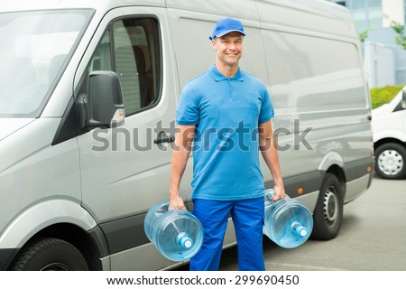 Delivery Man With Two Large Water Bottles Standing In Front Of Delivery Van