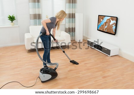 Young Woman Cleaning Floor With Vacuum Cleaner At Home