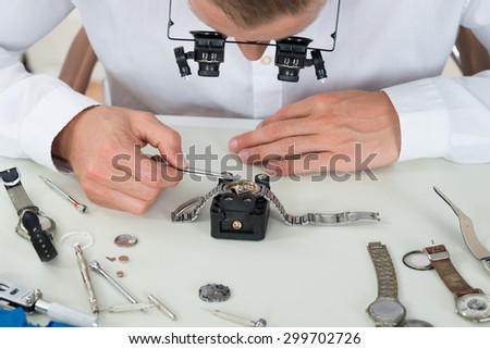 Close-up Of Young Man Repairing Wrist Watch At Desk In Workshop