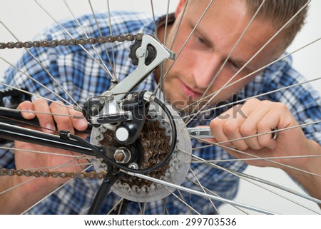 Close-up Of Young Man Repairing Bicycle With Spanner
