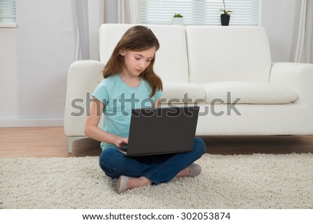 Girl Sitting In Front Of Sofa Using Laptop In Living Room