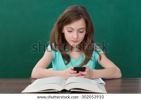 Girl Using Mobile Phone While Studying In Classroom