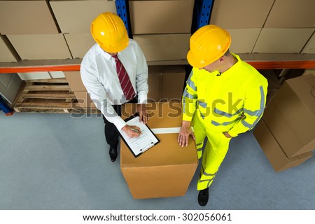 Warehouse Worker And Manager Checking Inventory In Warehouse