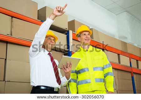 Warehouse Worker And Manager Checking The Inventory In A Large Warehouse