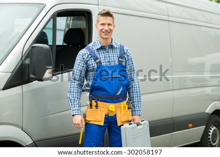 Young Repairman With Tools And Toolbox Standing In Front Of Service Van