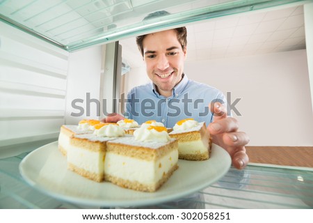 Portrait Of Young Handsome Man Taking Cake View From Inside The Refrigerator
