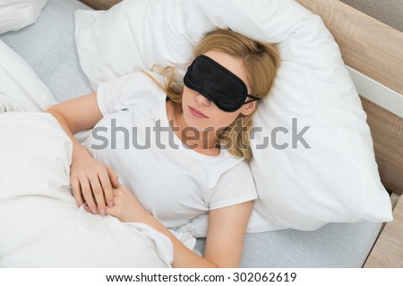 Young Woman Sleeping With Sleep Mask In Bedroom