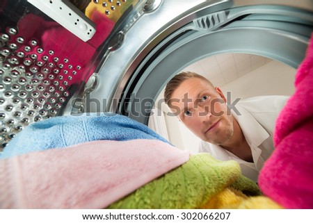 Close-up Of Man View From Inside The Washing Machine With Multi-colored Clothes