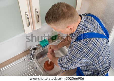 High Angle View Of Worker Pressing Plunger In Steel Kitchen Sink