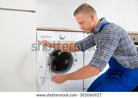 Young Male Technician In Overall Fixing Washing Machine